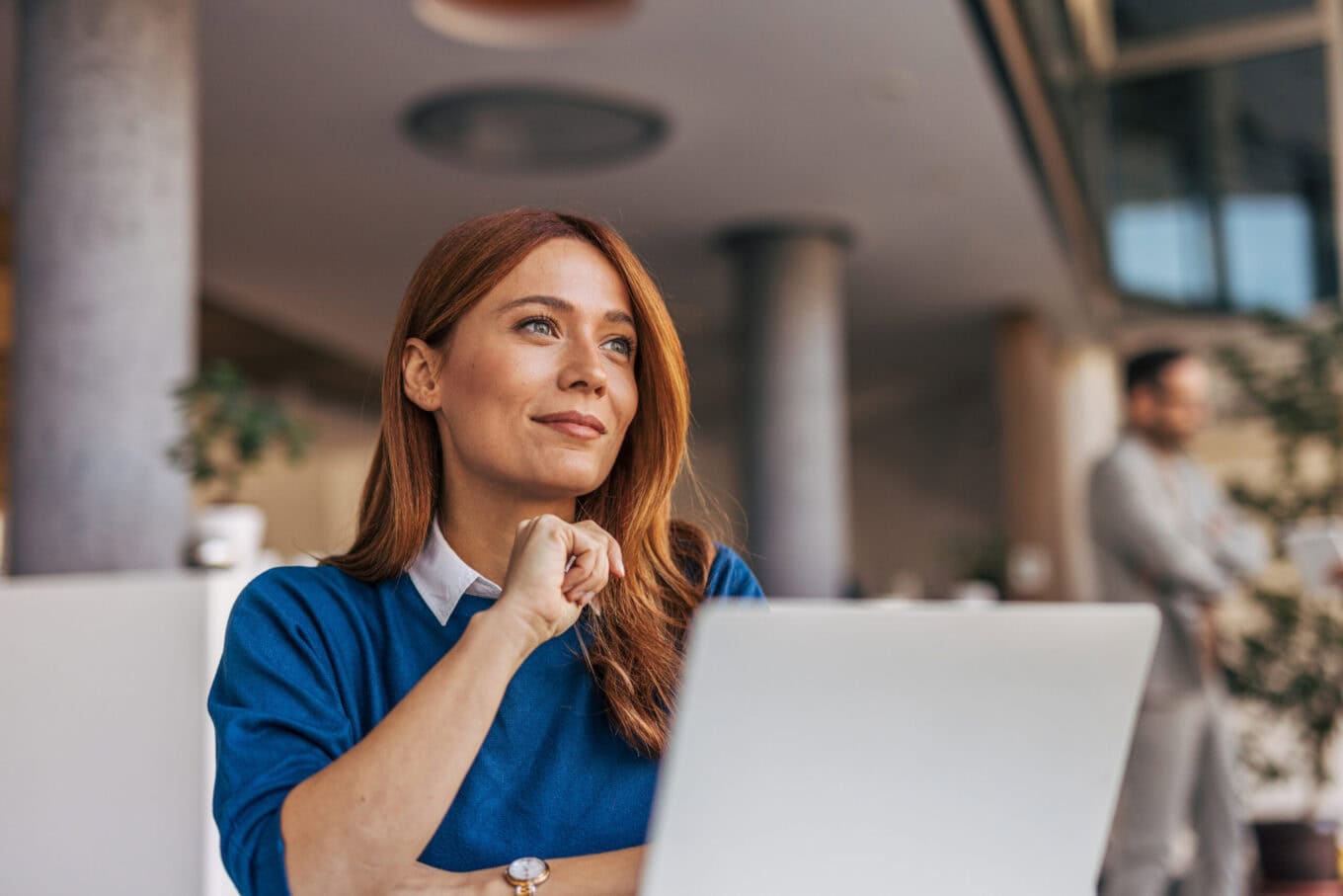 Frau mit Laptop bei Zeitarbeit, konzentriert und nachdenklich, in einem modernen Büro, symbolisiert professionelle Personaldienstleistungen und flexible Arbeitslösungen.