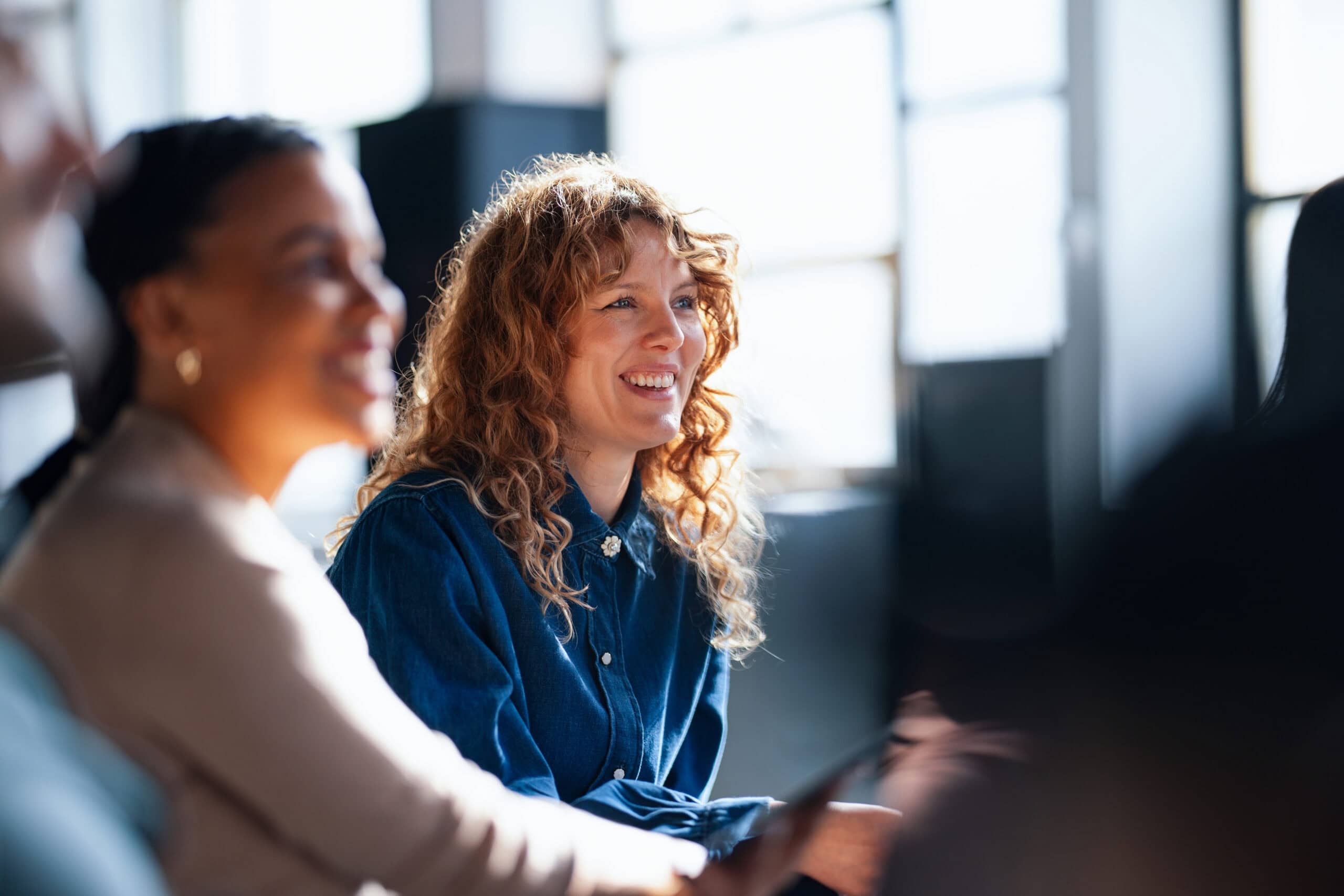 Zwei Frauen in einem modernen Büro bei einer Besprechung, die sich über Personalvermittlung und Contracting-Services austauschen.