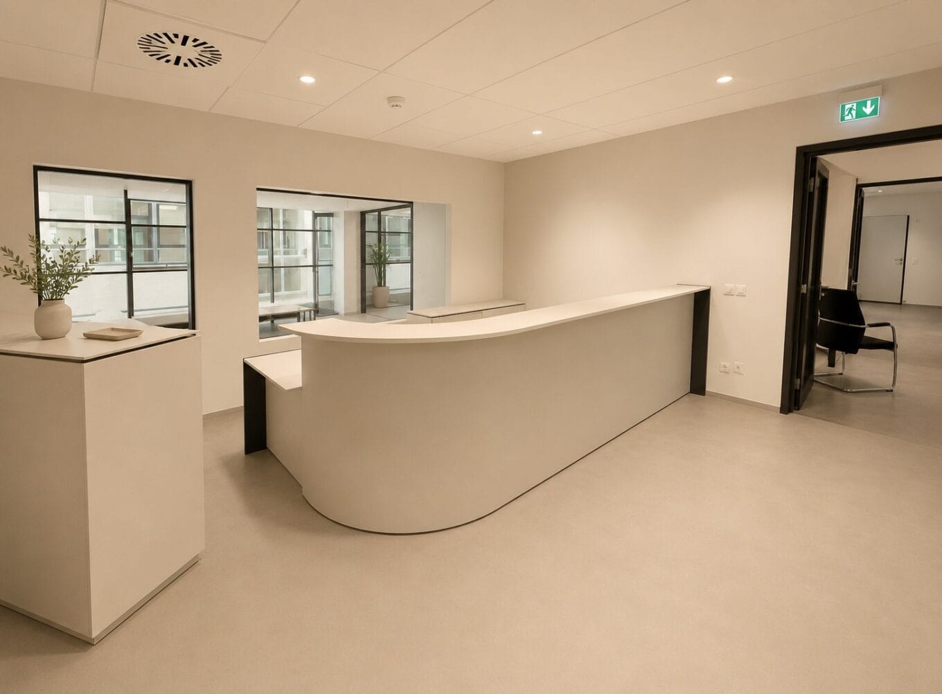 Zonă modernă de recepție într-un birou, cu un ghișeu alb, ferestre mari și un decor minimalist, ideală pentru comunicarea profesională a companiei.